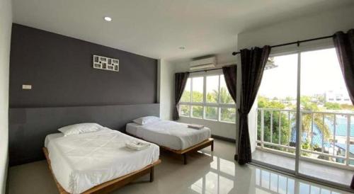 a bedroom with two beds and a large window at The Most Hotel in Ban Thai Wat Khot
