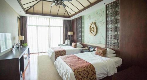 a hotel room with two beds and a desk at Lanxi Xingmao Resort Hotel in Wangchenggang