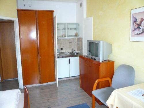 ein Wohnzimmer mit einem TV und einer Küche in der Unterkunft Hotel-Restaurant Nord-Stuv in Cuxhaven