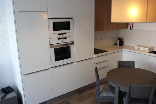a kitchen with white cabinets and a table with chairs at Apartamentos Turisticos da Nazare in Nazaré