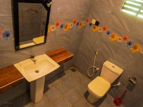 a bathroom with a sink and a toilet and a mirror at Difference Rajarata Hotel in Anuradhapura