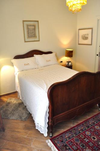 a bedroom with a large wooden bed with white sheets at Le Macine Relais in Cairo Montenotte