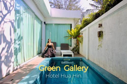 a woman sitting on a porch next to a pool at Green Gallery Beach Boutique Hotel in Hua Hin