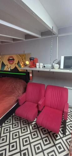 een kamer met twee roze stoelen en een bed bij studio pop art in Saint-Philbert-sur-Risle