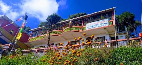 a building with a balcony with flowers in front of it at Lama homestay in Darjeeling
