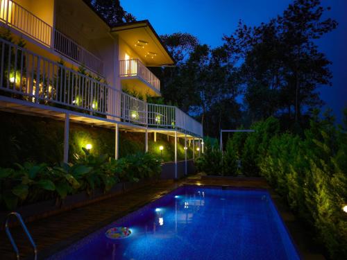a swimming pool in front of a building at night at Ice Cloud Munnar Pool Resort in Munnar