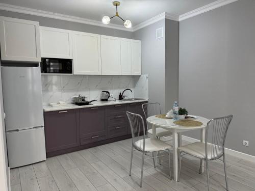 eine Küche mit Tisch und Stühlen und einem Kühlschrank in der Unterkunft ЖК Only sun в 10 минутах от Аэропорта in Prigorodnyy
