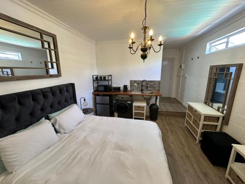 Un dormitorio con una cama blanca grande y un escritorio en Studio Seabiscuit, en Ciudad del Cabo