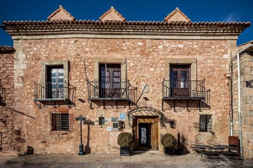 an old brick building with balconies and tables on it at Hotel Spa Salinas de Imón in Imón