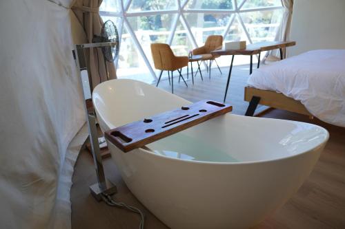 bañera blanca junto a la cama en Rabwa Geodesic Dome, en Misfāh