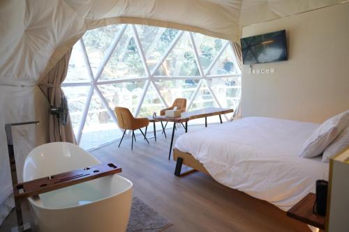 Un dormitorio con una cama y un escritorio y una ventana. en Rabwa Geodesic Dome, en Misfāh