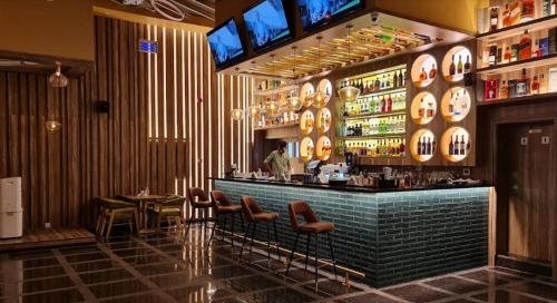 a bar in a restaurant with a man standing behind it at Tula Thaara Duplex with Private Beach and Pool in Al Marjan Island in Ras al Khaimah
