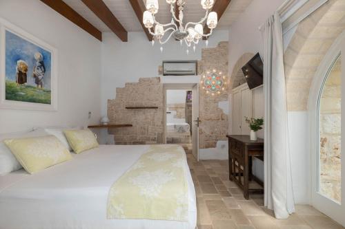 ein Schlafzimmer mit einem großen weißen Bett und einem Kronleuchter in der Unterkunft Trulli Rosalinda Luxury in Antonelli