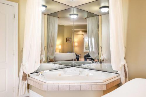 une baignoire dans une pièce avec un grand miroir dans l'établissement Days Inn by Wyndham Berthierville, à Berthierville
