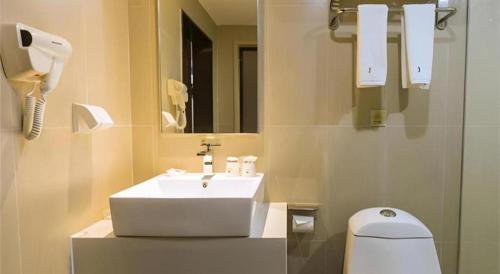 a bathroom with a sink and a toilet and a mirror at Jtour Inn Suizhou Yanhe Avenue in Suizhou