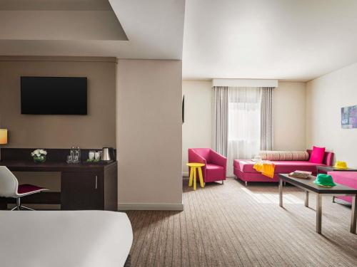 a living room with pink furniture and a couch at ibis Styles Sharjah in Sharjah