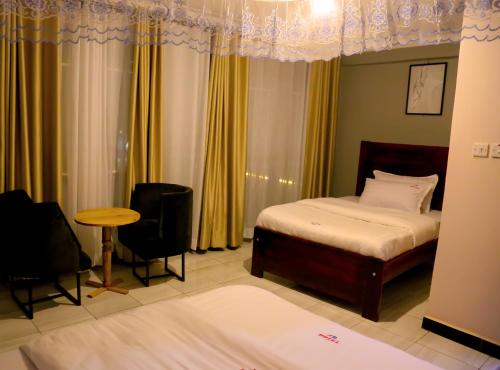 Un dormitorio con dos camas y una mesa y sillas. en JD LUXURY HOTEL Jinja, en Nalakonge