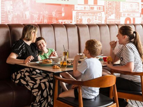 two women and two children eating at a table in a restaurant at Ibis Styles Hobart in Hobart