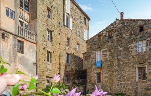 a hand holding up pink flowers in front of two buildings at 3 Bedroom Awesome Apartment In Olmeto in Olmeto