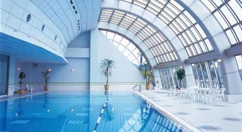einem großen Pool in einem Gebäude mit einer Decke in der Unterkunft Hotel Harvest Nankitanabe in Kitahara