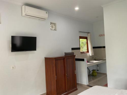 Cette chambre dispose d'une télévision murale et d'une armoire. dans l'établissement Cabin D Bendul and Warung, à Tabanan