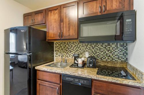 a kitchen with a stainless steel refrigerator and a sink at MainStay Suites Near Denver Downtown in Denver