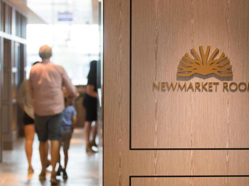 Um homem caminhando por um corredor com uma placa da Newmarketrustrust. em The William Inglis Mgallery em Warwick Farm