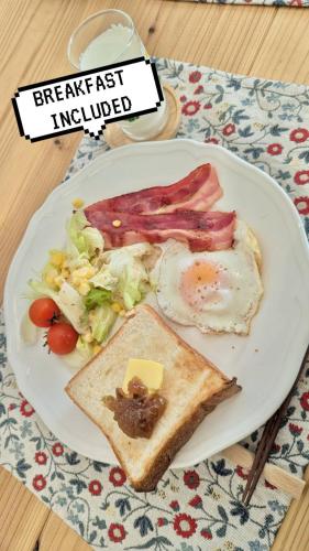 Un plato de desayuno con huevos, tocino y ensalada. en Mybound Homestay Zushi, en Zushi