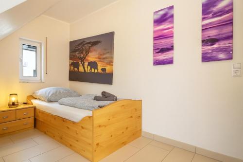 a bedroom with a wooden bed and paintings on the wall at Deluxe Apartment Diamond in Friedrichshafen
