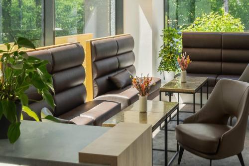 a waiting room with chairs and tables and plants at Wyndham Garden Munich Messe in Munich