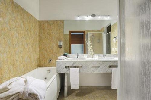 a bathroom with a tub and a sink and a bath tub at Relax Hotel Acquaviva - Tuscany Hills in Lucciana