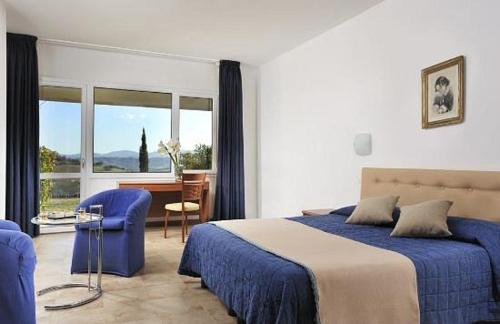 a bedroom with a bed and a desk and a window at Relax Hotel Acquaviva - Tuscany Hills in Lucciana
