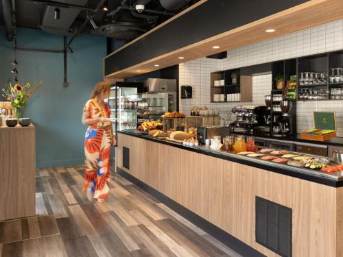 una mujer parada en el mostrador de una panadería en Adagio Antwerp City Center, en Amberes