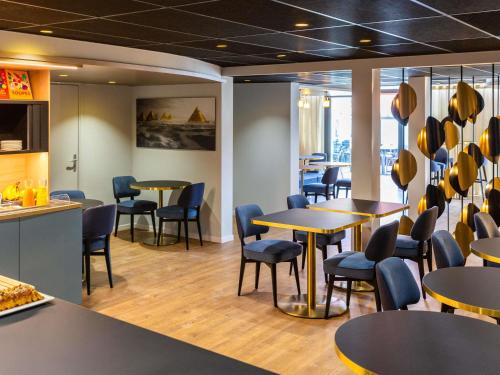 Un restaurante con mesas y sillas en una sala. en Mercure Toulouse Aeroport Blagnac, en Blagnac