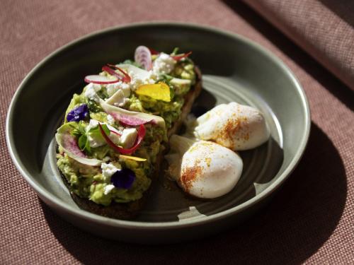 Un plato con un sándwich y huevos en una mesa. en Pullman Sydney Penrith, en Penrith