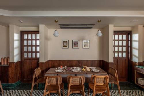 uma sala de jantar com mesa e cadeiras de madeira em Abode Jaipur em Jaipur
