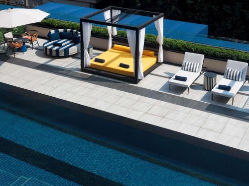 a pool with chairs and a gazebo next to a swimming pool at TRIBE Living Bangkok Sukhumvit 39 by AccorHotels in Bangkok