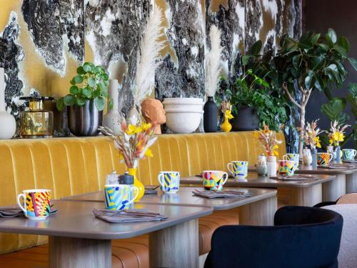 Una fila de mesas con plantas en una pared. en Pullman Lyon, en Lyon