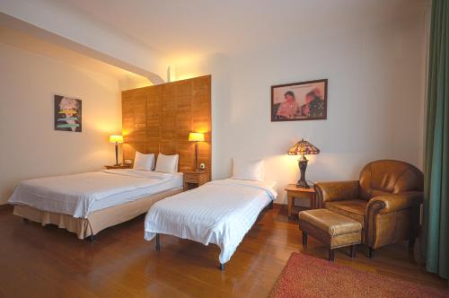 a hotel room with two beds and a chair at Rembrandt Old Town in Bucharest