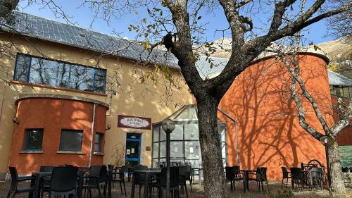 un bâtiment avec des tables et des chaises à côté d'un arbre dans l'établissement Hotel Ristoro Cristallo Gran Sasso d'Italia, à Assergi
