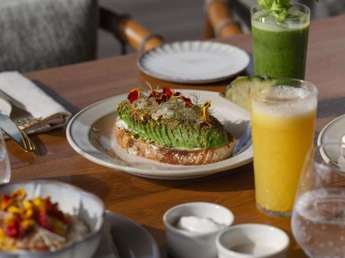 una mesa con un sándwich y un vaso de zumo de naranja en SO/ Maldives, en Atolón de Malé Sur