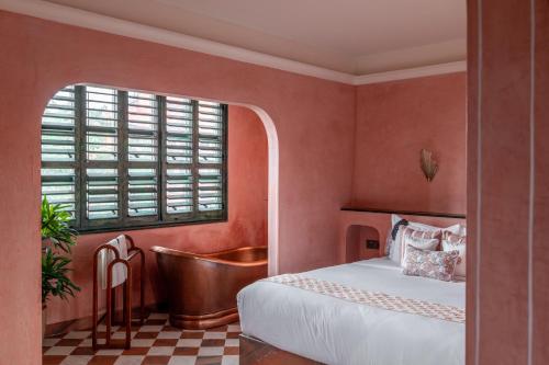 a bedroom with a bed and a tub next to a window at Abode Jaipur in Jaipur