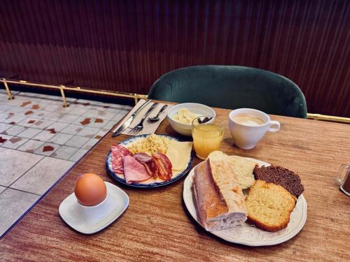 uma mesa com dois pratos de alimentos para o pequeno-almoço e um ovo em Greet Hotel Brest Aéroport em Guipavas