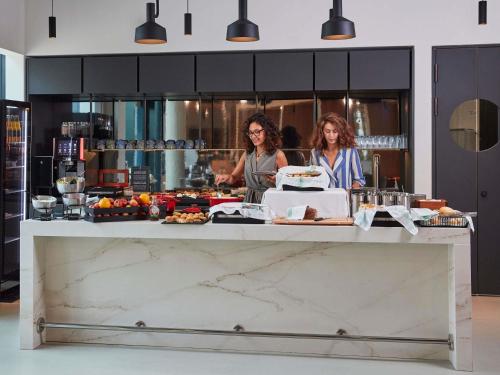 two women standing in a kitchen preparing food at Aparthotel Adagio Heidelberg in Heidelberg
