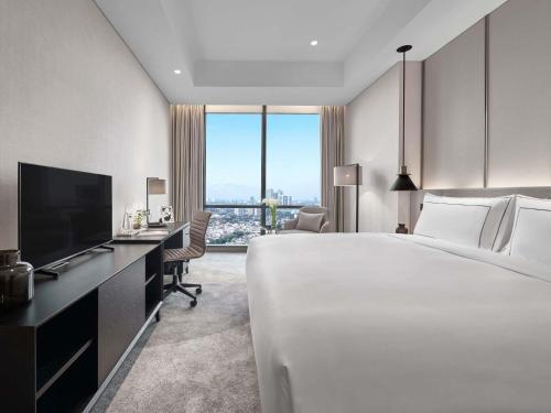 a hotel room with a large bed and a television at 25hours Hotel Jakarta The Oddbird in Jakarta