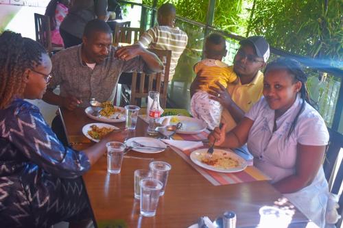 a group of people sitting around a table eating food at Big Spoon Cafe in Eldoret