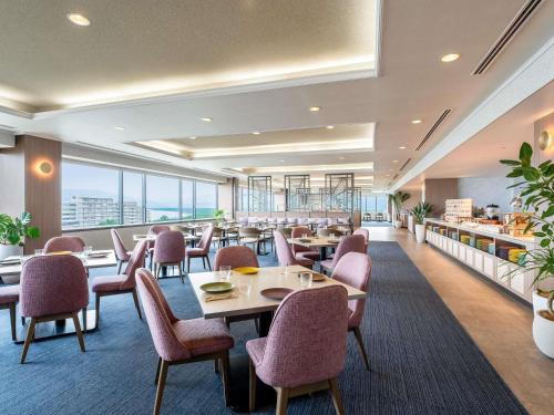 a restaurant with tables and chairs and windows at Mercure Saga Karatsu Resort in Karatsu