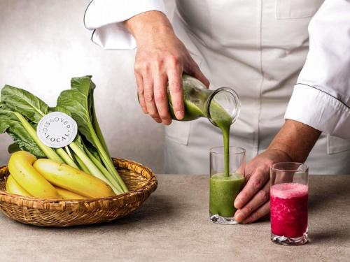 Um chef servindo suco verde em um copo ao lado de uma cesta de frutas. em Mercure Saga Karatsu Resort em Karatsu