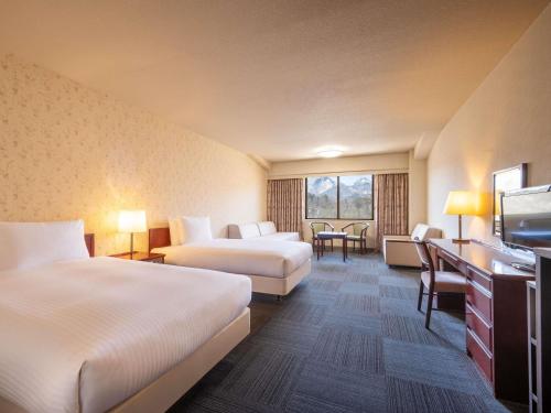 a hotel room with two beds and a television at Mercure Urabandai Resort & Spa in Kitashiobara