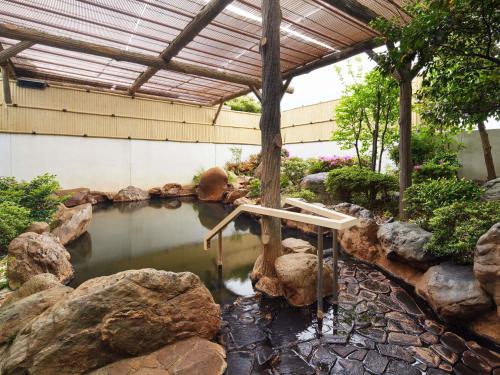a pool of water with rocks in a garden at Grand Mercure Lake Biwa Resort & Spa in Nagahama